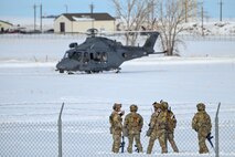 A group of Airmen talk near a helicopter.