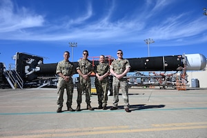 soldiers pose in front of a rocket