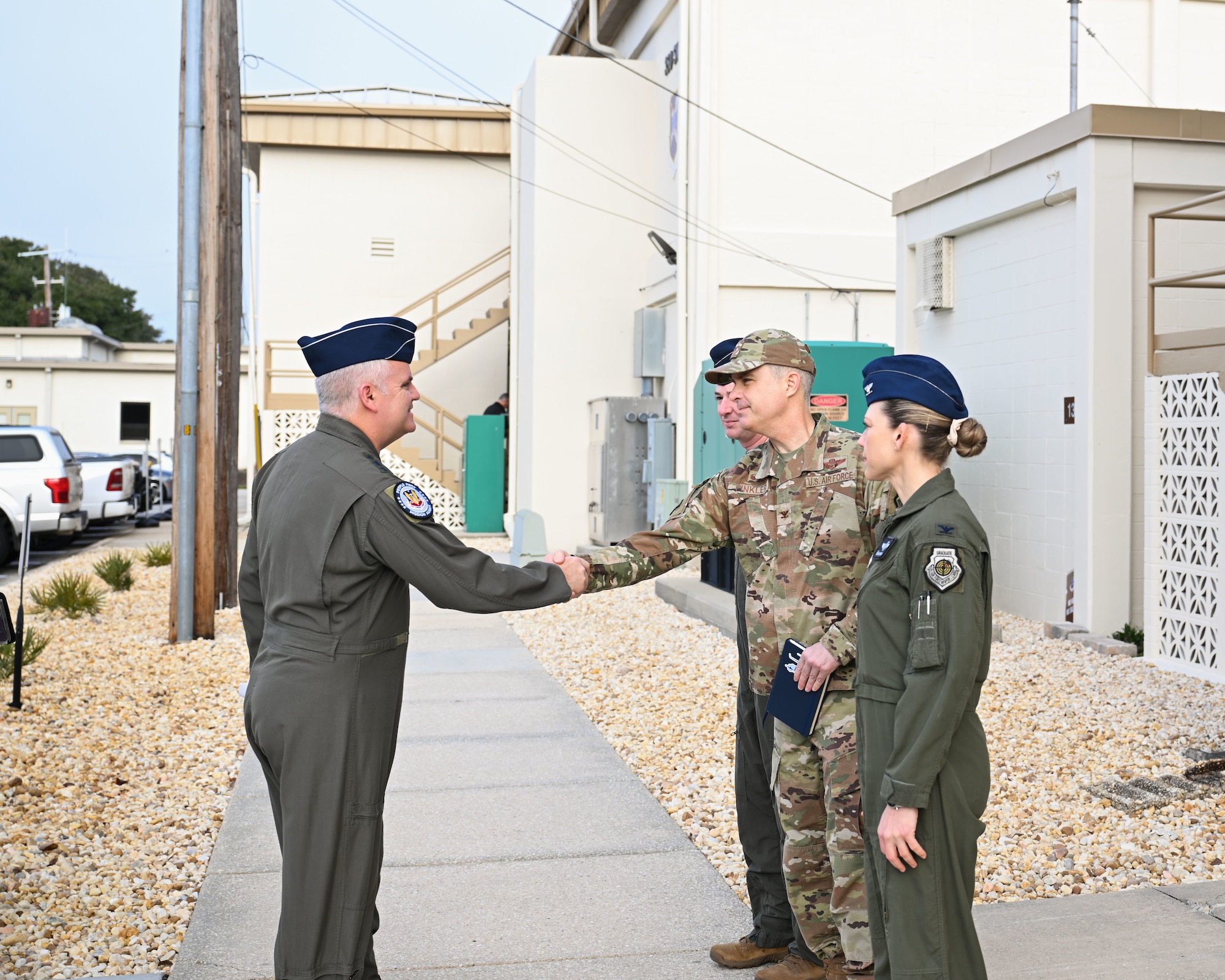 U.S. Air Force Lt. Gen. Michael Koscheski, Air Combat Command deputy commander, shakes hands with Col. Andrew Finkler, 850th Spectrum Warfare Group commander, alongside Col. Candice Sperry, 350th Spectrum Warfare Group commander,  during a visit to the 350th Spectrum Warfare Wing at Eglin Air Force Base, Florida, Jan. 30, 2025. The visit highlighted the 350th Warfare Wing’s efforts to integrate Electromagnetic Spectrum Operations into large-scale Air Force exercises like Bamboo Eagle 25-1.(U.S. Air Force photo by Senior Airman Anna Smith)