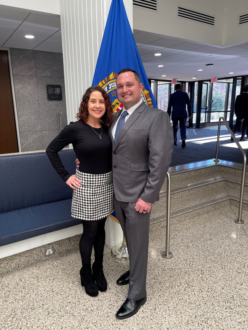 Lt. Col. Criss poses with wife in front of flag