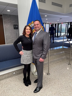 Lt. Col. Criss poses with wife in front of flag