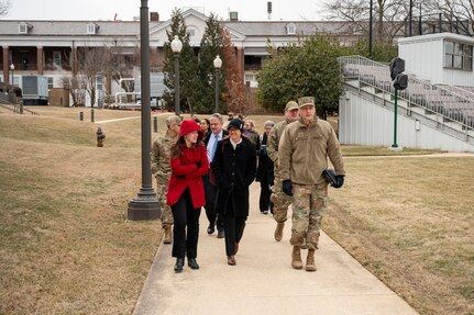 OSD and JBAB leadership walk across a base campus to tour dormitories.