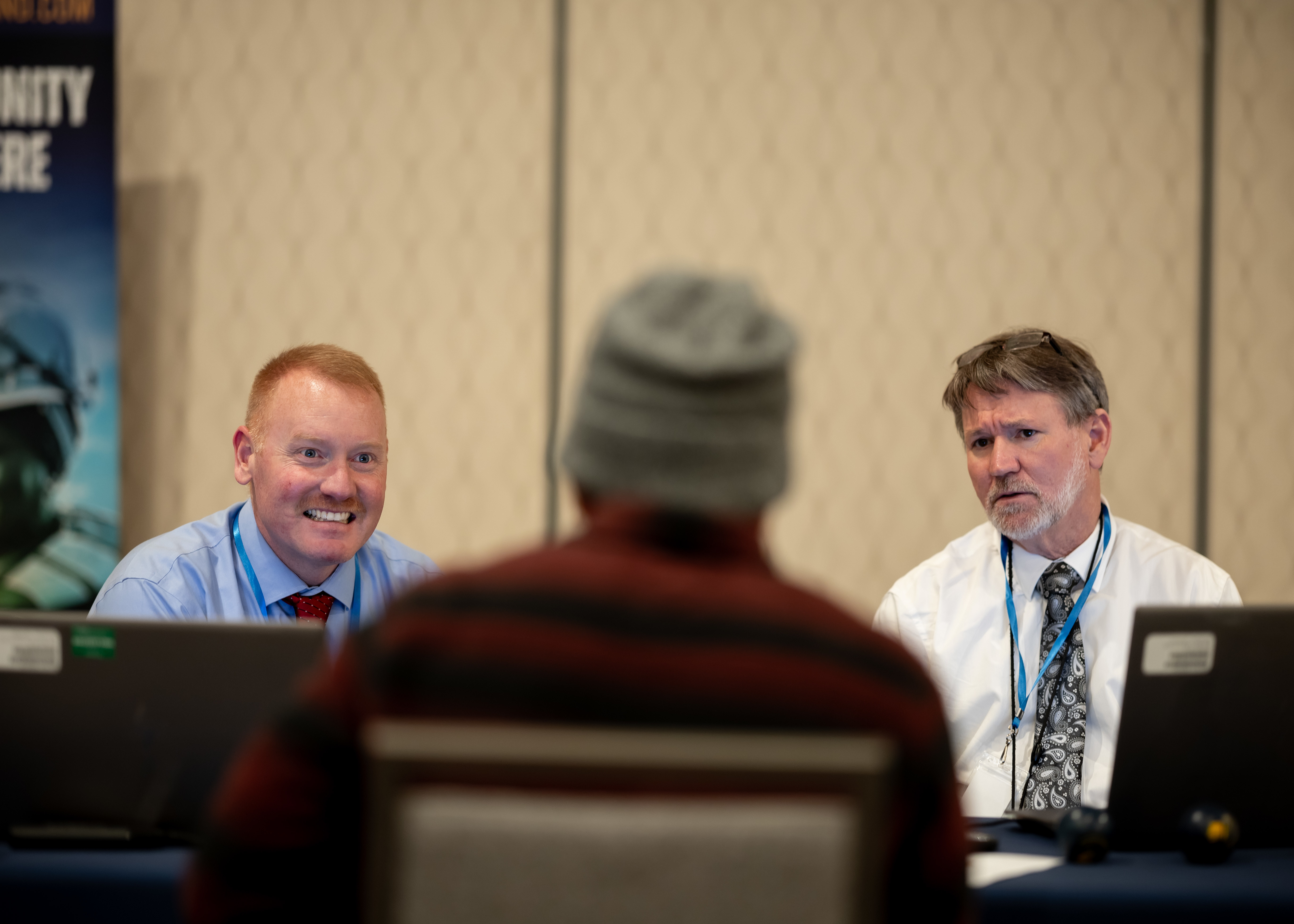 Matt Schroder, engineering competency manager with Military Sealift Command (MSC), left, and Ray Coleman, assistant port engineer supervisor SUP with MSC, Right, speak with a job seeker during Seafarers Day hosted by MSC at the Waterside Marriott in Norfolk Va. February 12, 2025. During the event, MSC personnel provided insights and shared career opportunities with attendees, helping them explore potential career paths.