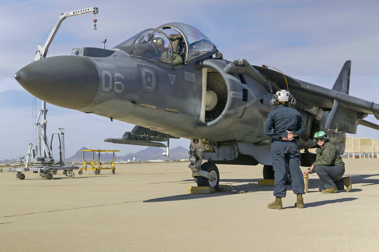 Marines remove military markings from an aircraft.
