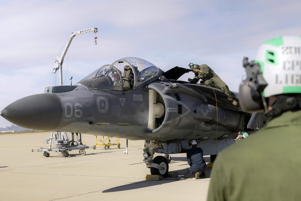 Marines remove military markings from an aircraft.