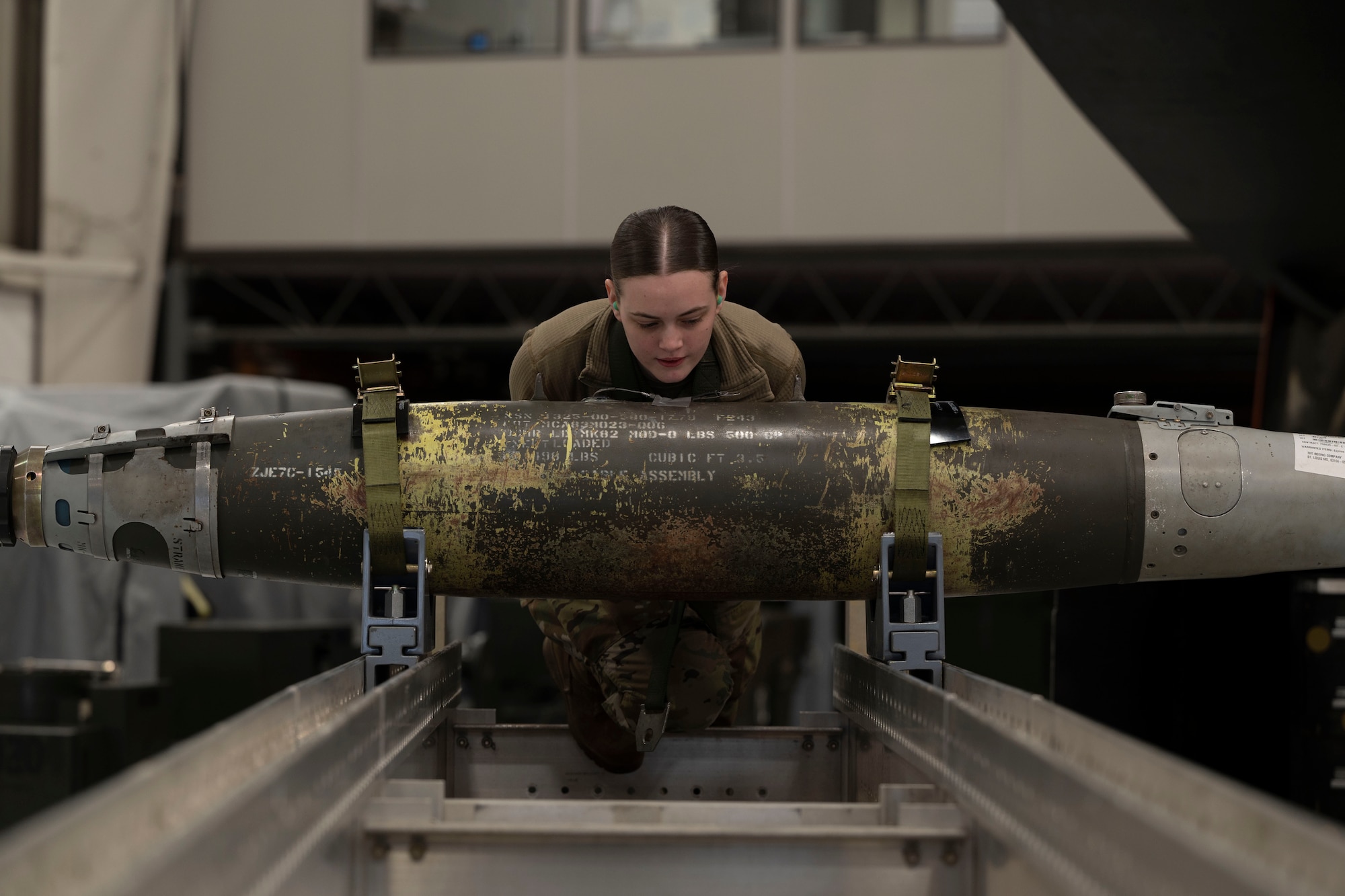 U.S. Airman 1st Class Leigha Little, 509th Aircraft Maintenance Squadron weapons load crew member, pushes a GBU-38 bomb during the annual weapons load crew competition at Whiteman Air Force Base, Mo., Jan 25, 2023.