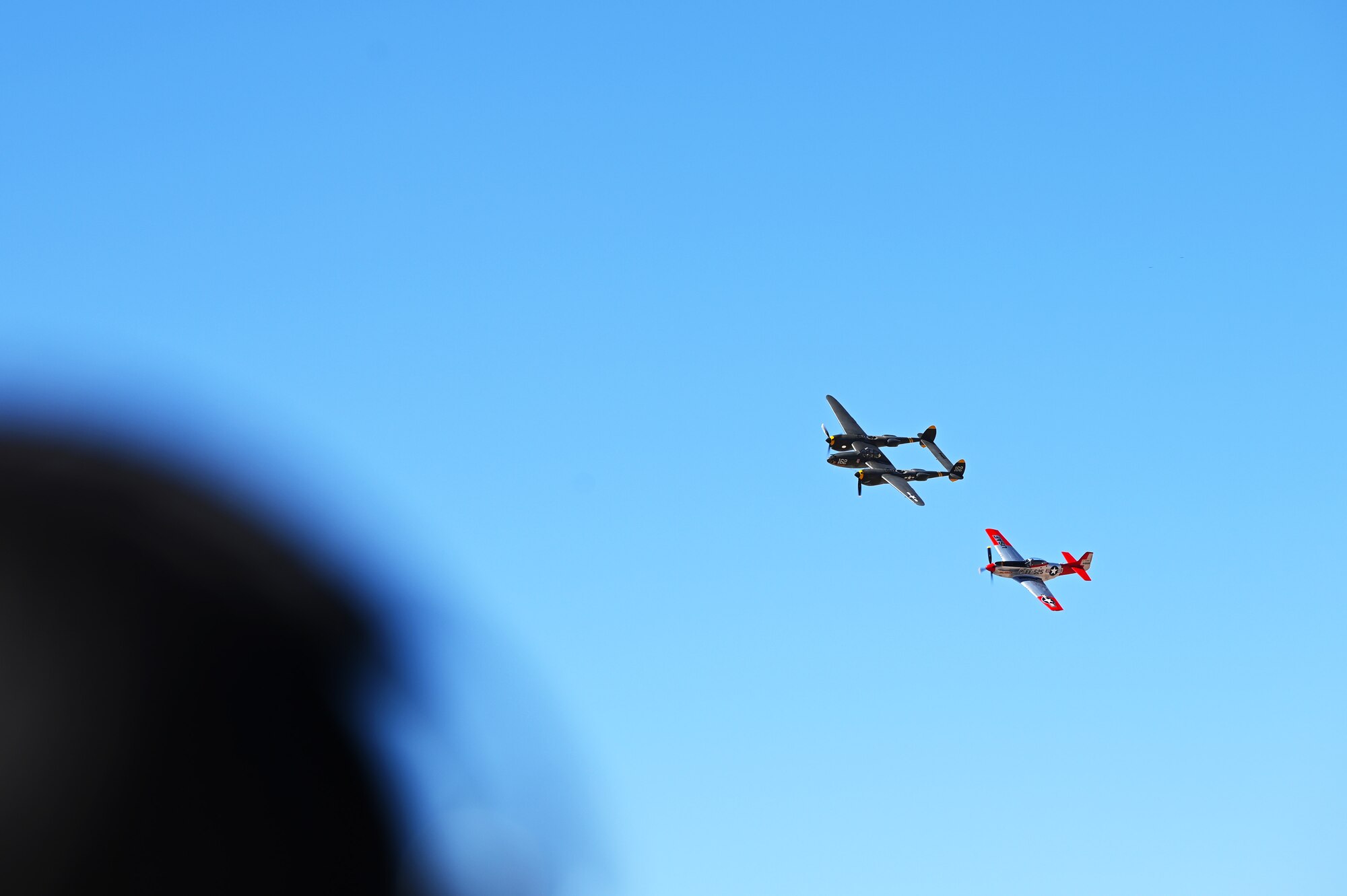 A P-38 Lightning and a P-51 Mustang aircraft fly in formation during the Heritage Flight Training Course at Davis-Monthan Air Force Base, Arizona, Feb. 27, 2025. The annual aerial demonstration training event has been held at D-M since 2001 and features aerial demonstrations from historical and modern fighter aircraft. (U.S. Air Force photo by Senior Airman Andrew Garavito)