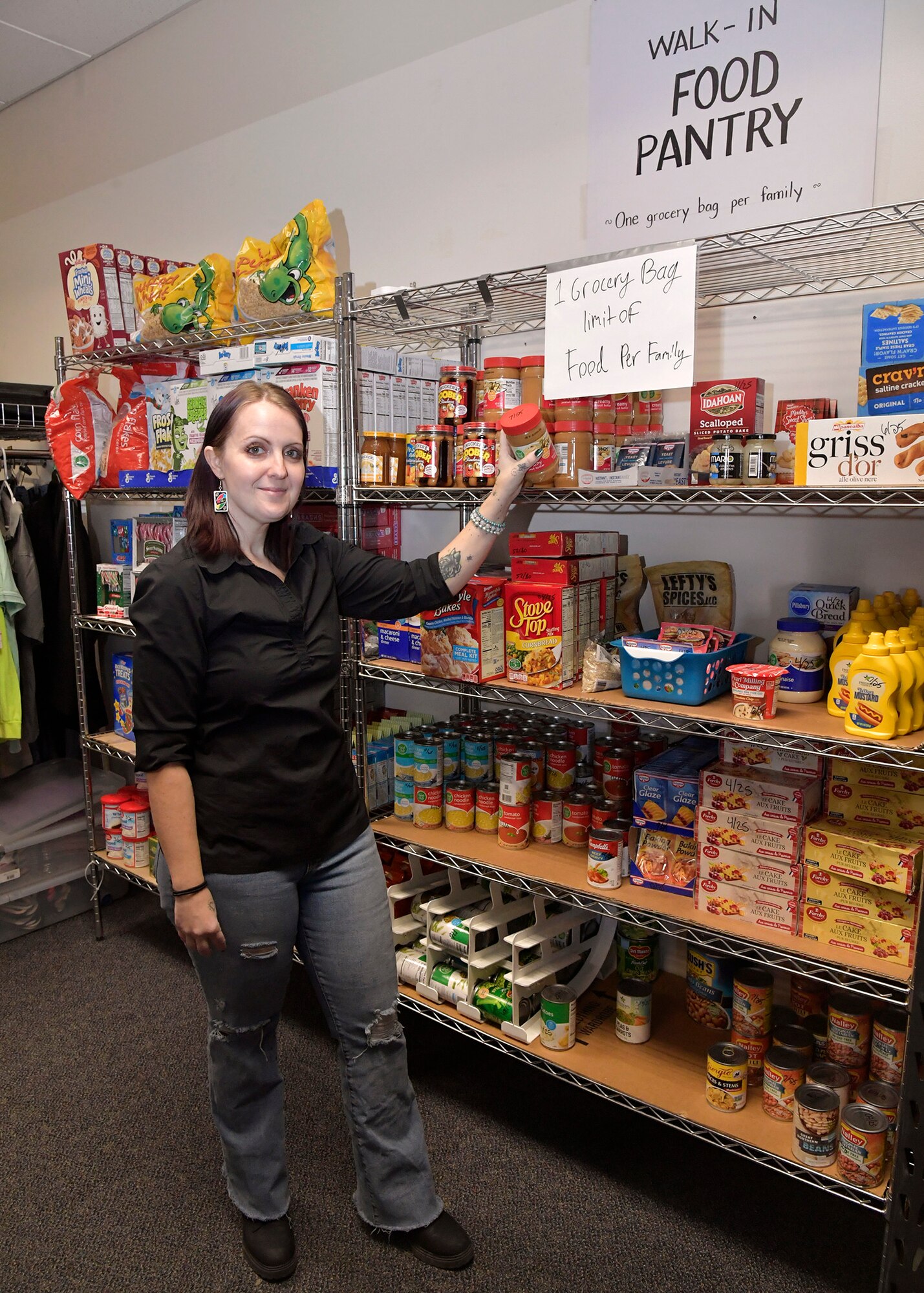 Woodwick stands next to shelves filled packaged food items.