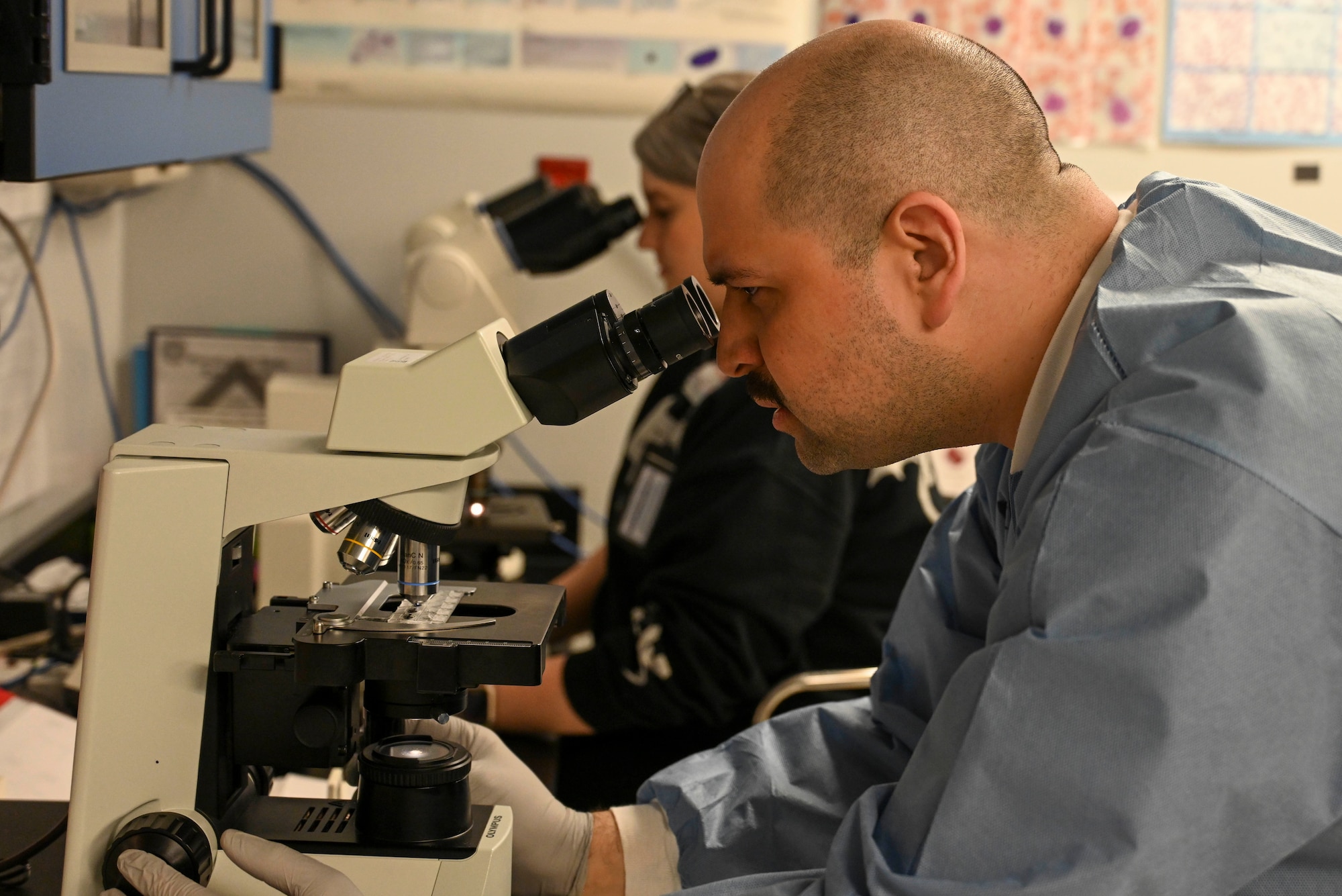 An officer looks through a microscope.