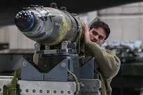 U.S. Air Force Senior Airman Curtis Campbell, 131st Aircraft Maintenance Squadron weapons load crew member, helps lift and guide a GBU-38 bomb into position to be moved to the bomb bay of the B-2 Spirit stealth bomber Weapons Load Trainer at Whiteman Air Force Base, Mo., Jan 26, 2024.