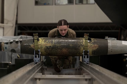 U.S. Airman 1st Class Leigha Little, 509th Aircraft Maintenance Squadron weapons load crew member, pushes a GBU-38 bomb during the annual weapons load crew competition at Whiteman Air Force Base, Mo., Jan 25, 2023.