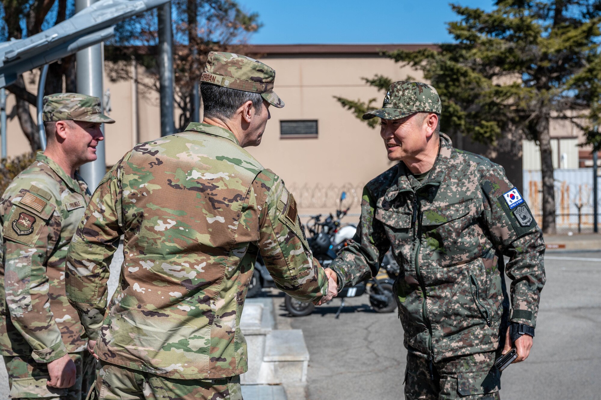 U.S. Air Force Chief Master Sergeant Joshua Trundle, 51st Fighter Wing command chief, left, and Col. William McKibban, 51st FW commander, center, greet Republic of Korea Army Brig. Gen. Jung Hwan Lee, Combined Forces Command C4 director, at Osan Air Base, ROK, Feb. 26, 2025. The CFC maintains operational control of more than 600,000 active-duty military personnel from all U.S. and ROK military branches.  (U.S. Air Force photo by Staff Sgt. Christopher Tam)