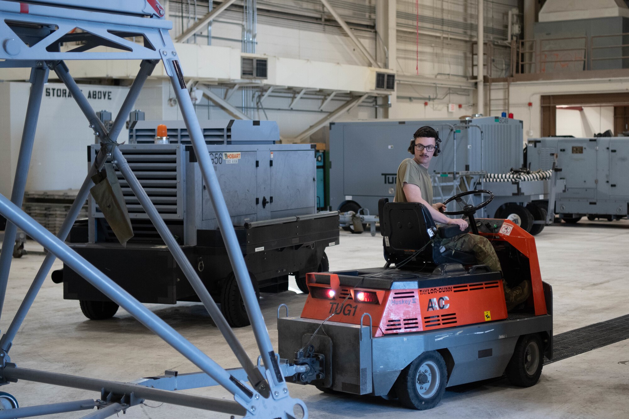 Airman 1st Class Nolan Clements, 22nd Maintenance Squadron aerospace ground equipment technician, operates a tug to back a stand through the AGE shop at McConnell Air Force Base, Kansas, Feb. 25, 2025. A tug is used to tow heavy equipment from place to place.