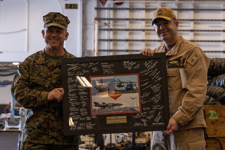 U.S. Marine Corps Maj. Gen. James B. Wellons, left, commanding general of 3rd Marine Aircraft Wing, presents a signed plaque to U.S. Navy Capt. Ryan Conole, executive officer of the Wasp-class amphibious assault ship USS Makin Island (LHD 8) as a thank you for a tour of the ship during the 3rd MAW Commander’s Course, at Naval Base San Diego, Feb. 26, 2025. The Commander's Course brought together leadership from across 3rd MAW to explore key topics ranging from science and technology, safety and unit culture, fostering readiness for future challenges, and enhancing understanding of the MAW's critical role in supporting I Marine Expeditionary Force objectives and the joint force. (U.S. Marine Corps photo by Lance Cpl. Jennifer Sanchez)
