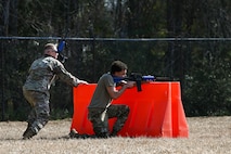 Two Airmen takes cover during a defensive fighting position familiarization course