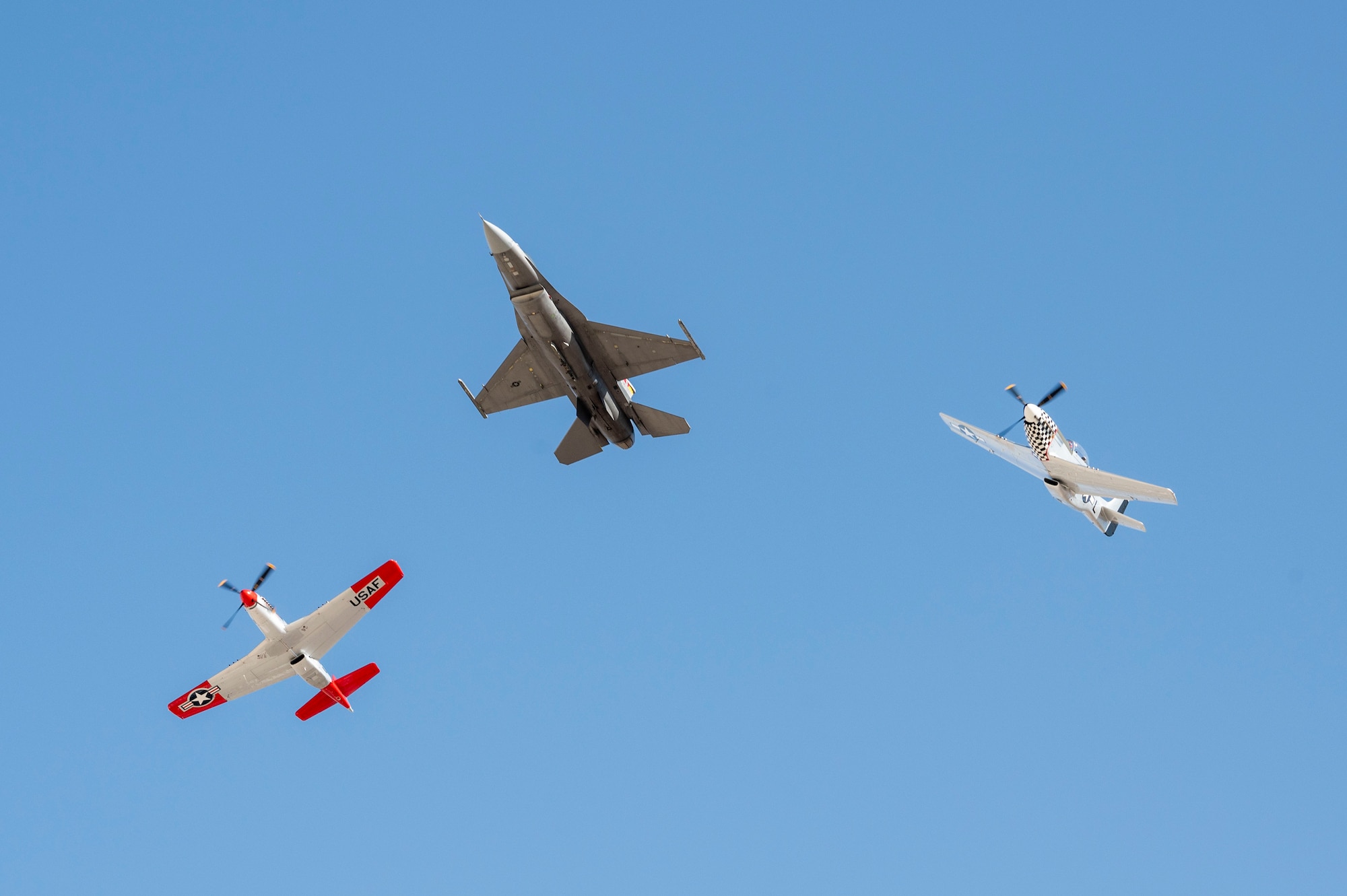 A U.S. Air Force F-16 Fighting Falcon and two P-51 Mustang aircraft break from formation during Heritage Flight Training Course at Davis-Monthan Air Force Base, Arizona, Feb. 28, 2025. The maneuver was just one of many acrobatic moves that the pilots performed (U.S. Air Force photo by Airman Samantha Melecio)