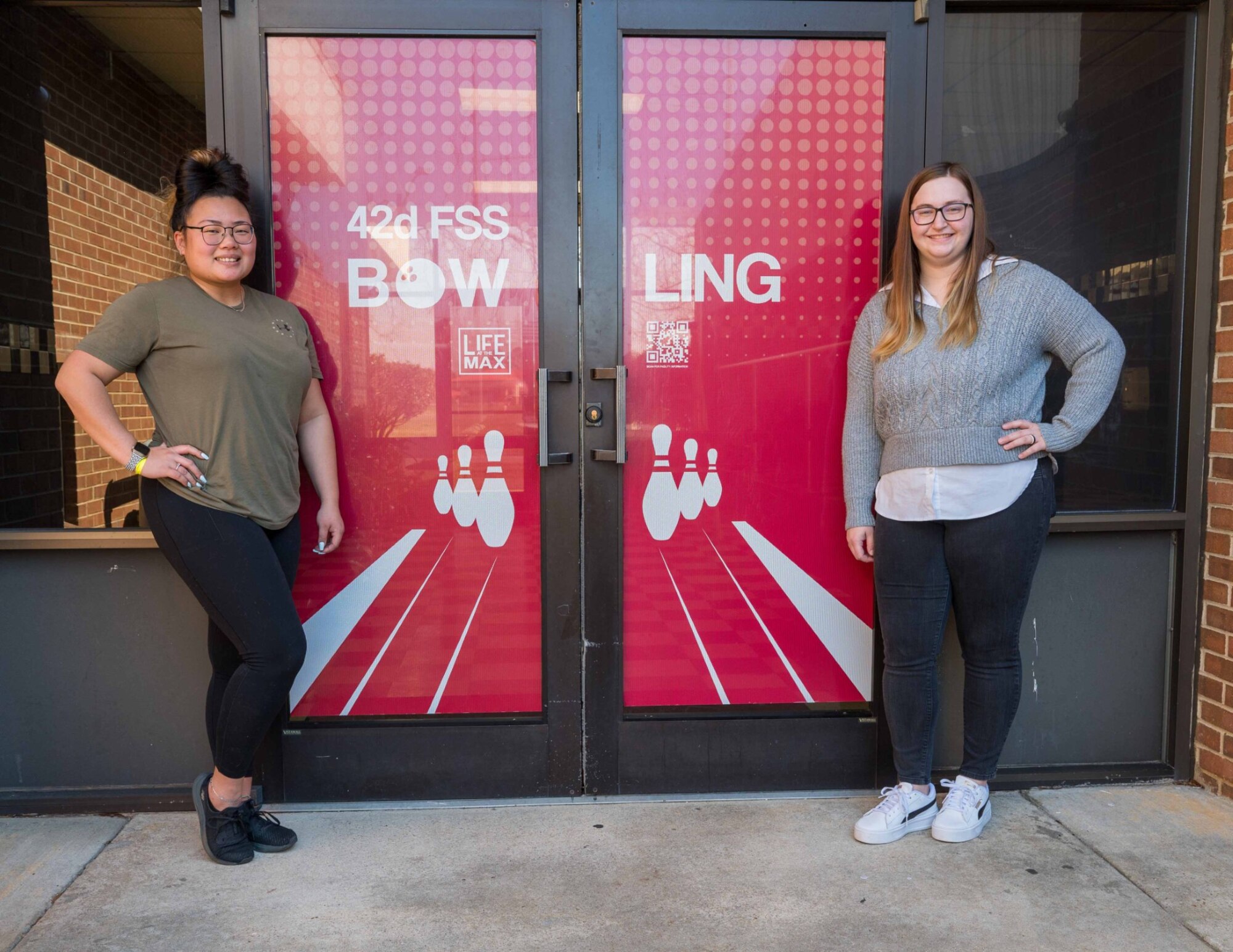 Haili Lombardo (left), Maxwell Bowling Center recreation aide and Tessa Stembridge, Maxwell Bowling center assistant manager, pose for a photo in front of the Maxwell Bowling Center at Maxwell Air Force Base, Ala. Feb. 26, 2025.