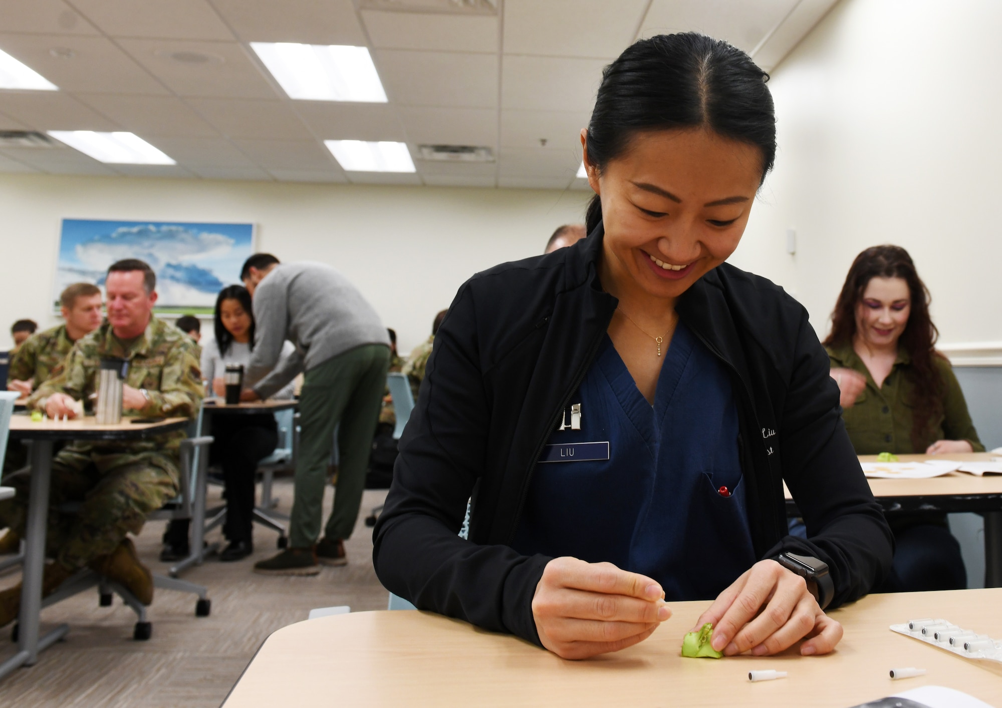 Female Airmen sticks a needle into a piece of broccoli during Battlefield Acupuncture.
