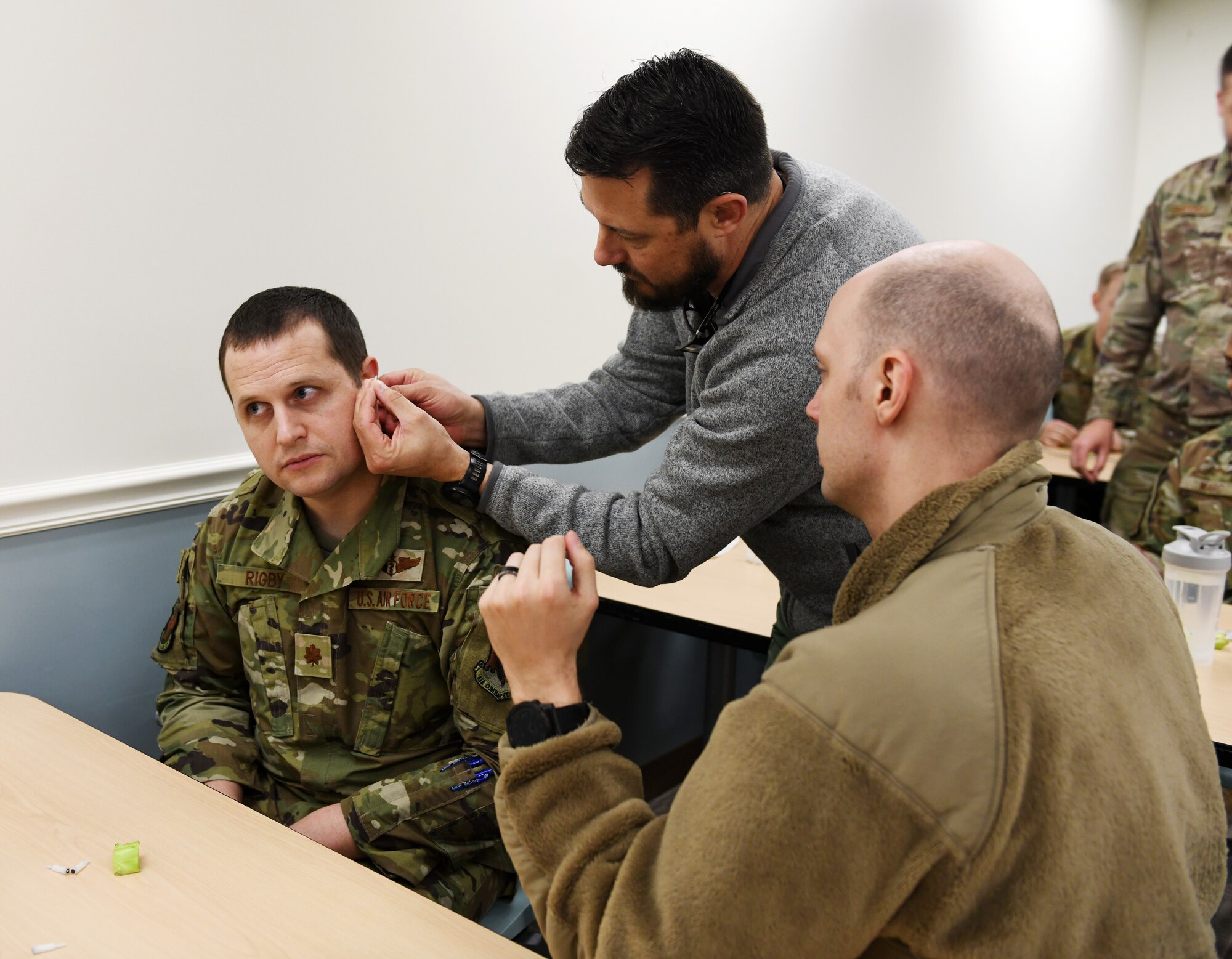 Airmen points to a PowerPoint slide where the pain relief markers are located in a ear during Battlefield Acupuncture Training.