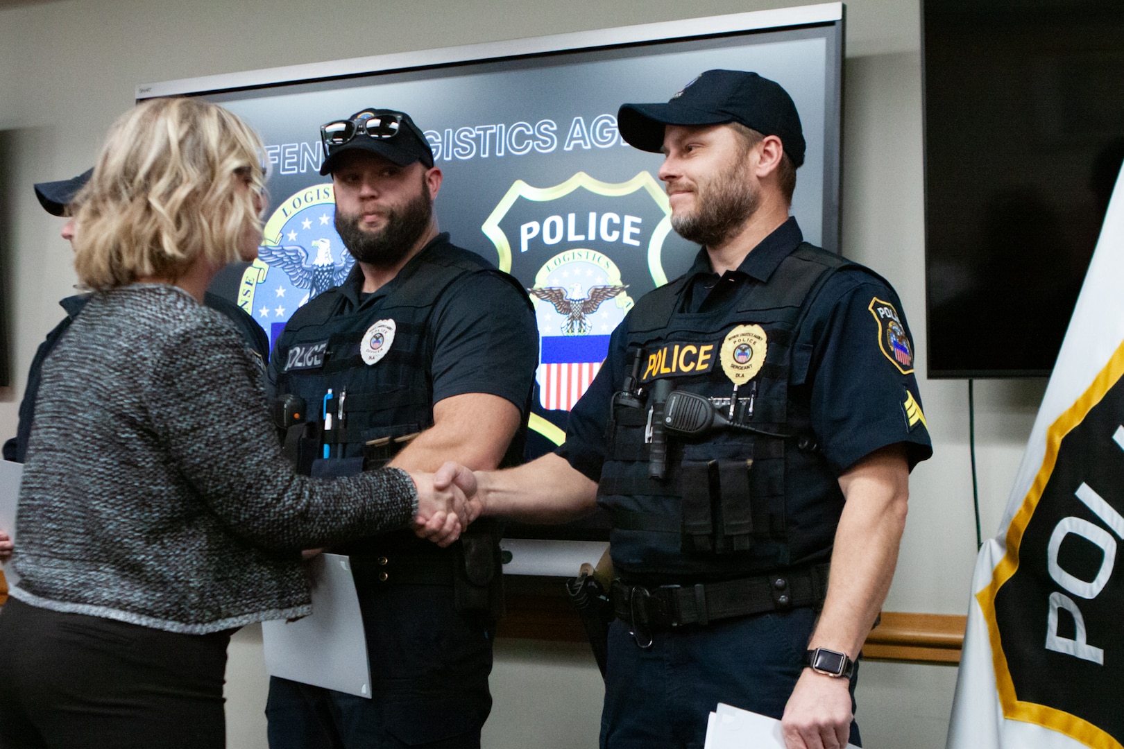 A man wearing a police uniform shakes a woman's hand.