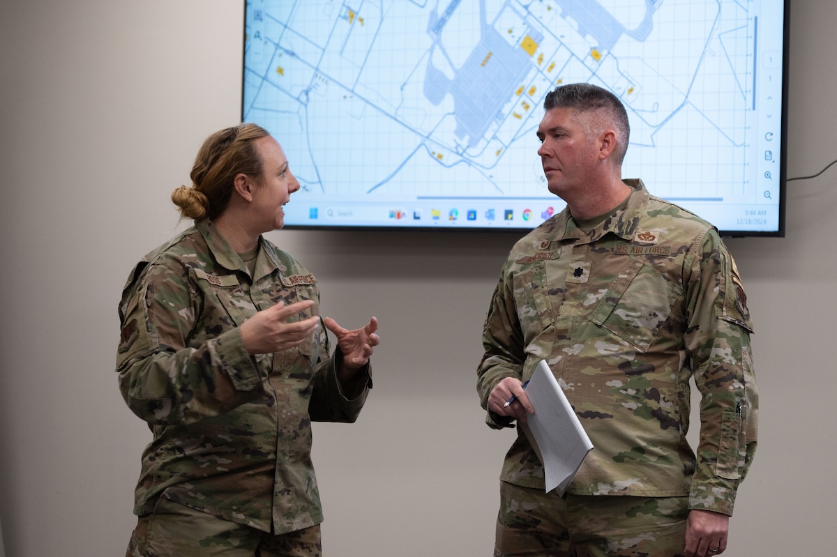 Airmen speak to each out in front of map.