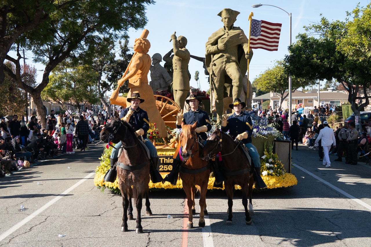 Three mounted soldiers pose in front of a parade float carrying statues and the American flag down a street.