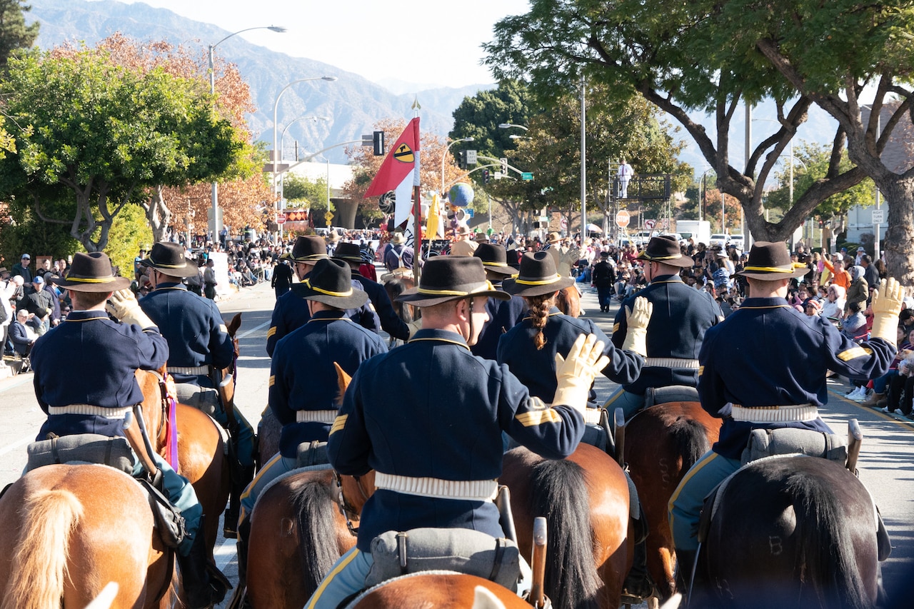 A group of mounted soldiers move down a parade street.