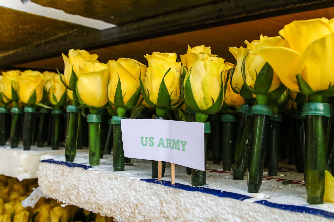 False yellow flowers stand in rows in Styrofoam in front of a label that says U.S. Army.