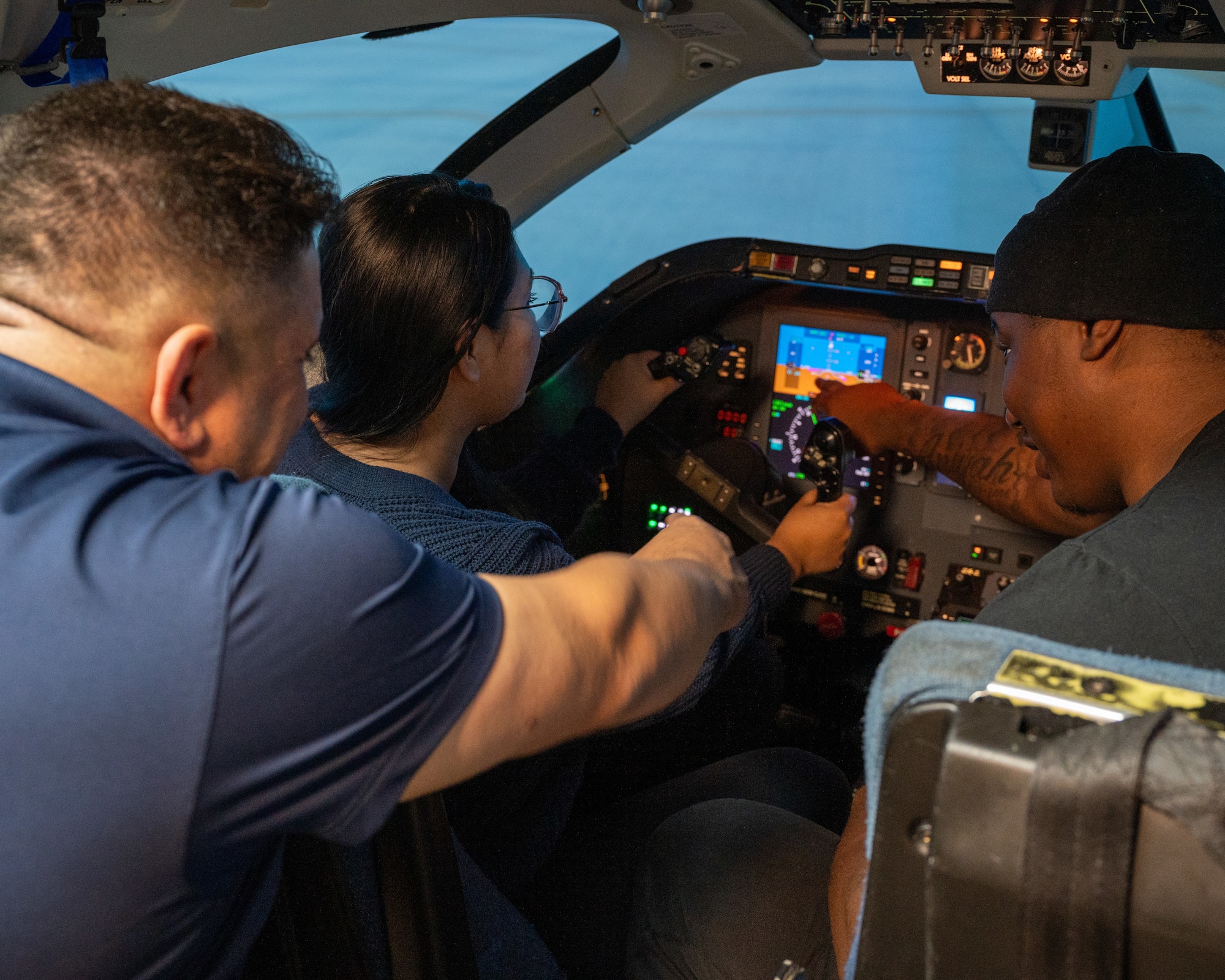 Airmen sit in the cockpit of a T-1A Jayhawk simulator while being guided by retired Col Andy "Gatos" Katz, at Laughlin Air Force Base, Texas, Dec. 17, 2024. To honor the legacy of the T-1A Jayhawk, Airmen took part in red carpet simulators, being able to practice flying the T-1. (U.S. Air Force photo by Staff Sgt. Nicholas Larsen)