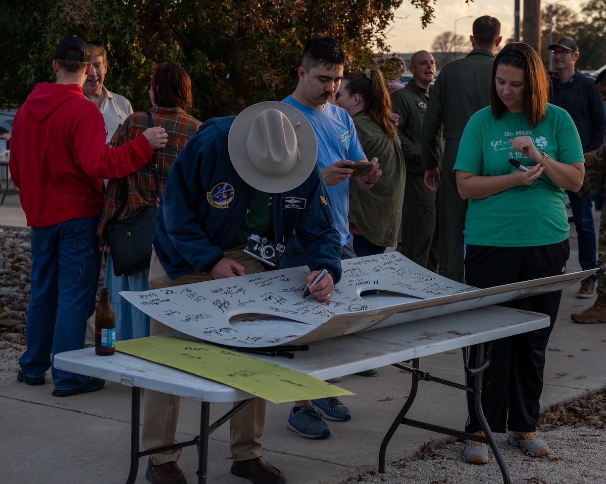 Airmen sign the interior panel of a T-1A Jayhawk at Laughlin Air Force Base, Texas, Dec. 16, 2024. Airmen of the 86th Flying Training Squadron held a barbecue and ceremony to celebrate the legacy of the T-1A. (U.S. Air Force photo by Staff Sgt. Nicholas Larsen)