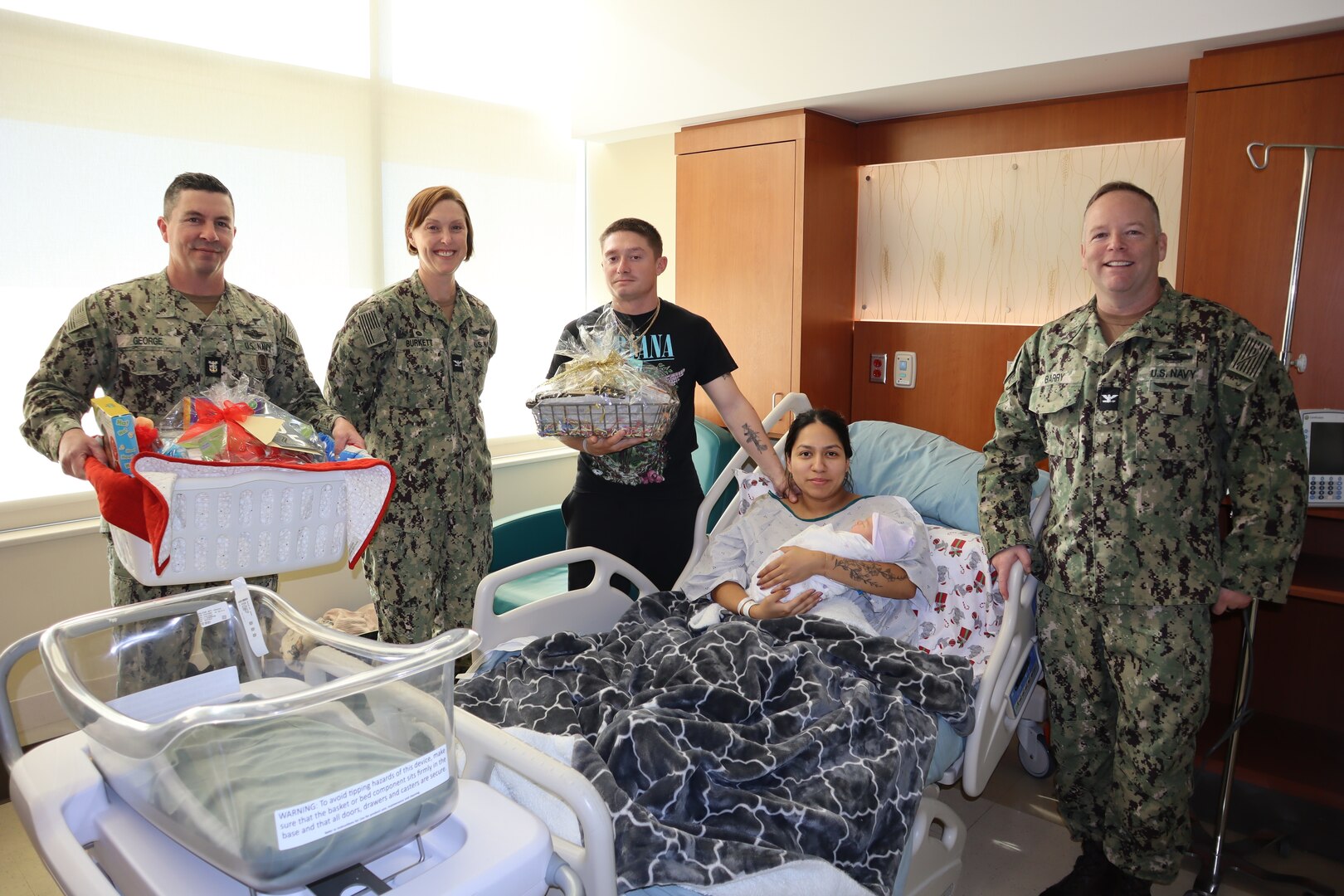 Lance Cpl. Alondra Salazar and Lance Cpl. Deandre Rutherford pose with their newborn baby, Andreas E. Rutherford-Salazar, on Jan. 2, 2025, in the Maternal Infant Services Department of Naval Hospital Camp Pendleton. Baby Andreas was the first baby born at NHCP in 2025. Salazar is assigned to 1st Maintenance Battalion, 1st Marine Logistics Group, I Marine Expeditionary Force and Rutherford is assigned to 2nd Battalion, 4th Marine Regiment, 31st Marine Expeditionary Unit, Okinawa, Japan. Joining the happy couple and Baby Andreas are the hospital Triad of Master Chief Petty Officer Wayne George, command master chief, Navy Capt. Jenny S. Burkett, hospital director, and Navy Capt. Michael J. Barry, hospital executive officer.