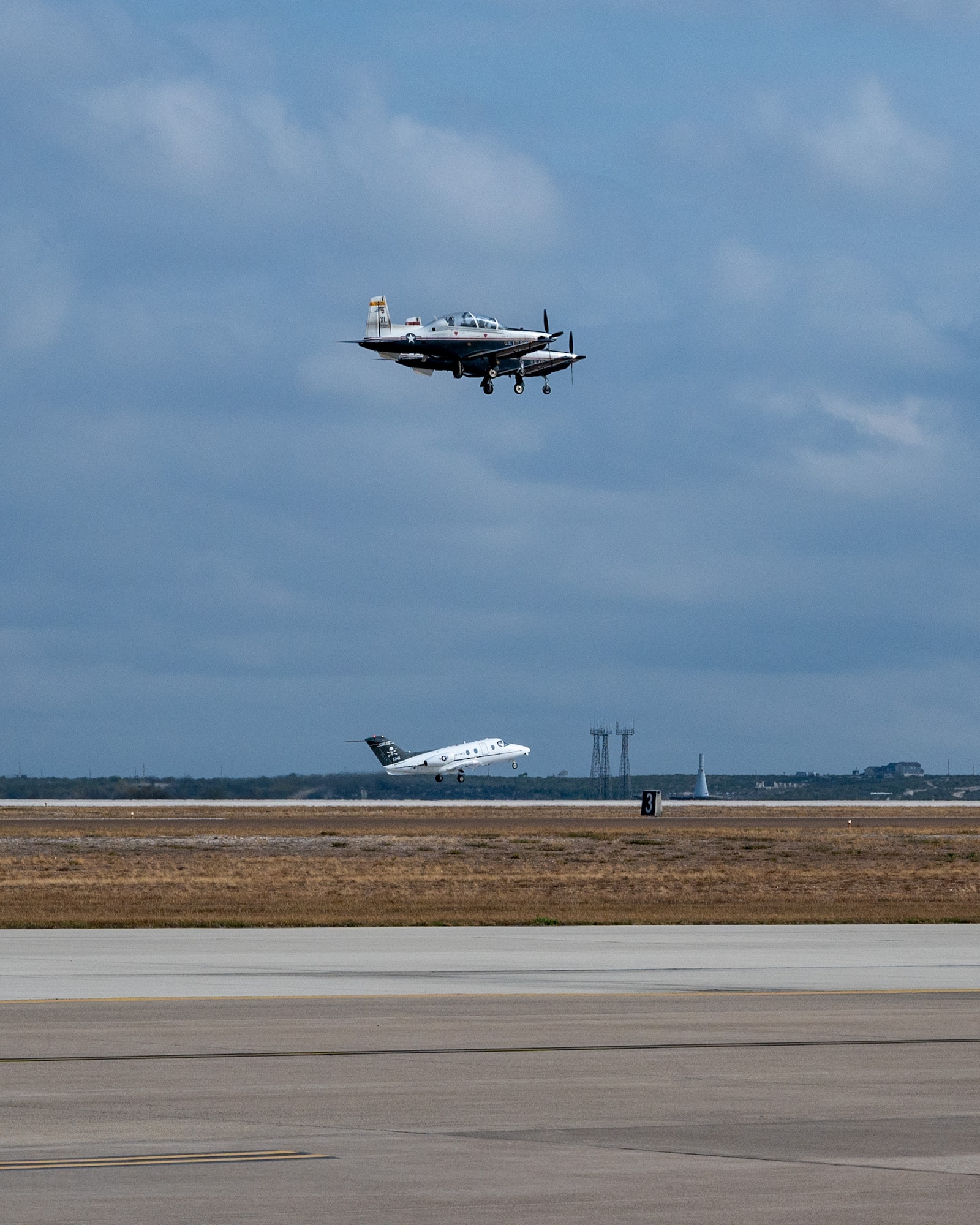 The final T-1A Jayhawk takes off while a pair of T-6A Texan IIs begin their flight at Laughlin Air Force Base, Texas, Dec. 17, 2024.  To mark the end of its 31 year service, the final T-1A took part in a two-pass, five-ship flyover of the Air Traffic Control tower and the flightline. (U.S. Air Force photo by Staff Sgt. Nicholas Larsen)