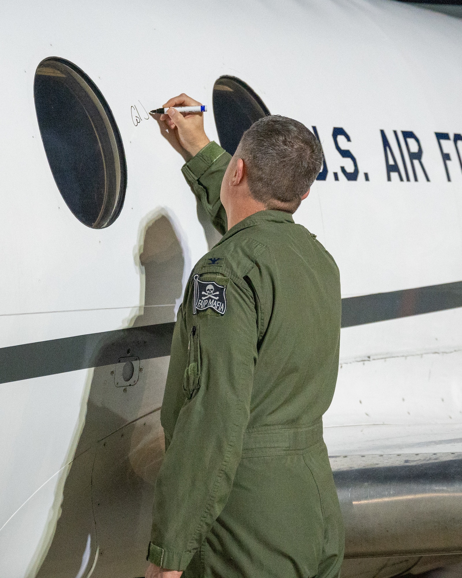 U.S. Air Force Col. Joseph "Angry" McCane, 47th Operations Group commander, signs the last T-1A Jayhawk at Laughlin Air Force Base, Texas, Dec. 16, 2024. Airmen from all over the base signed the final Jayhawk at Laughlin. (U.S. Air Force photo by Staff Sgt. Nicholas Larsen)