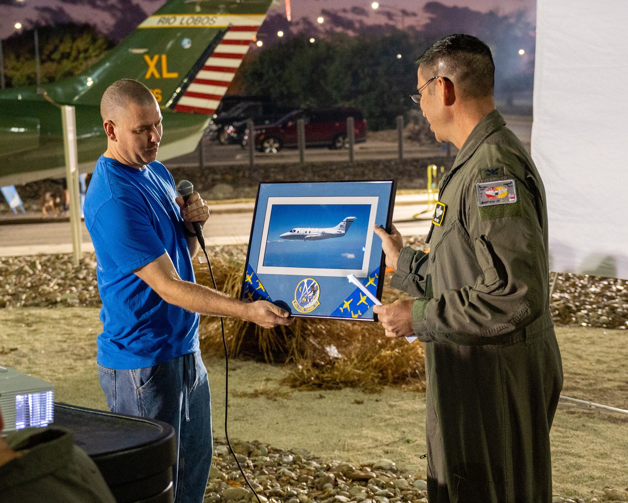 U.S. Air Force Lt. Col Nathan Hedden, 86th Flying Training Squadron (FTS) commander, presents a plaque to retired Col James Muniz, 86th FTS instructor pilot, at Laughlin Air Force Base, Texas, Dec. 16, 2024. Airmen of the 86th Flying Training Squadron held a barbecue and ceremony to celebrate the 31 years of service the T-1A Jayhawk had at Laughlin. (U.S. Air Force photo by Staff Sgt. Nicholas Larsen)