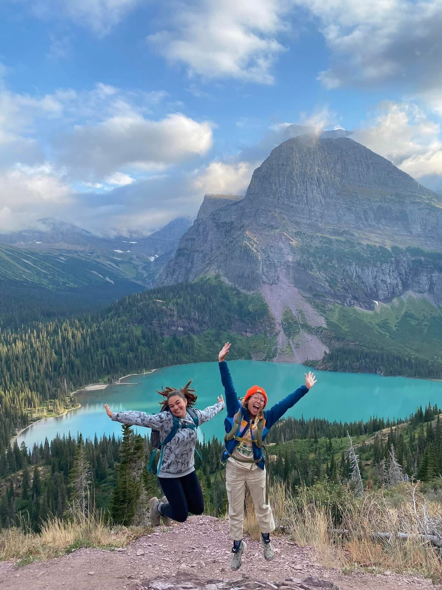 Lauren Torres (left), 97th Air Mobility Wing Public Affairs apprentice, and her friend jump for a photo at Glacier National Park, Montana. Torres took a trip to Glacier National Park with friends while she was living and working in Yellowstone National Park. (courtesy photo)