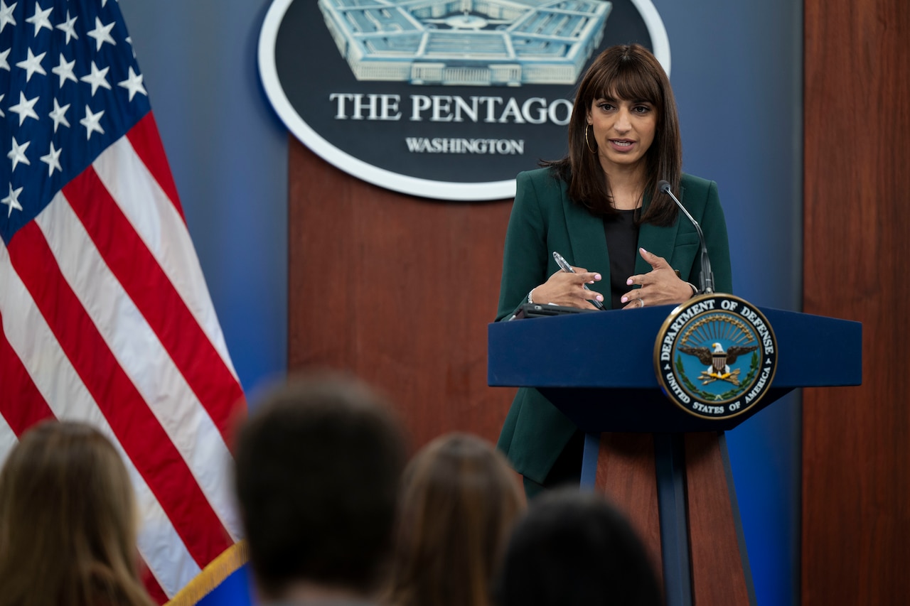 A woman speaks to an audience from a podium.
