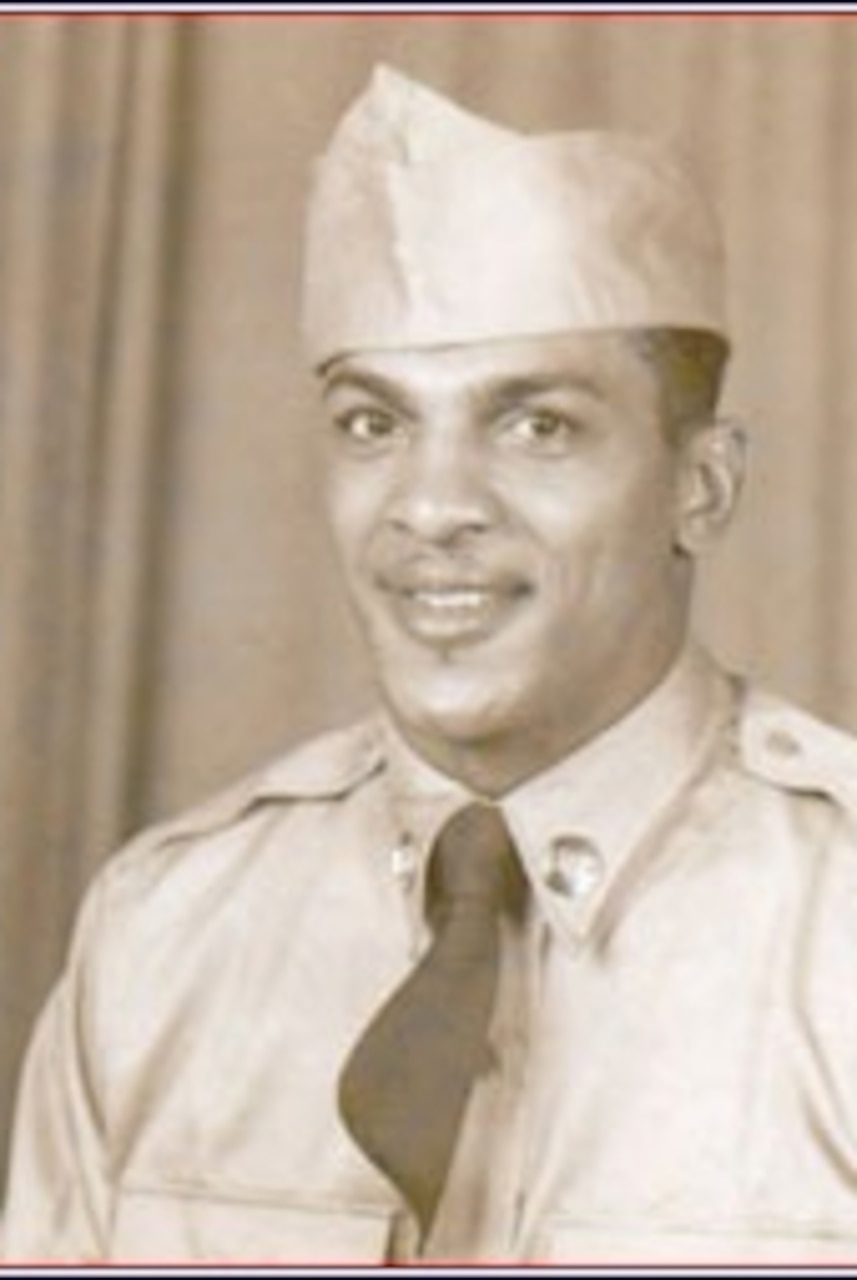 A man poses for a portrait photo wearing combat uniform.