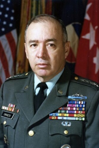 A man poses for a portrait photo wearing combat uniform.