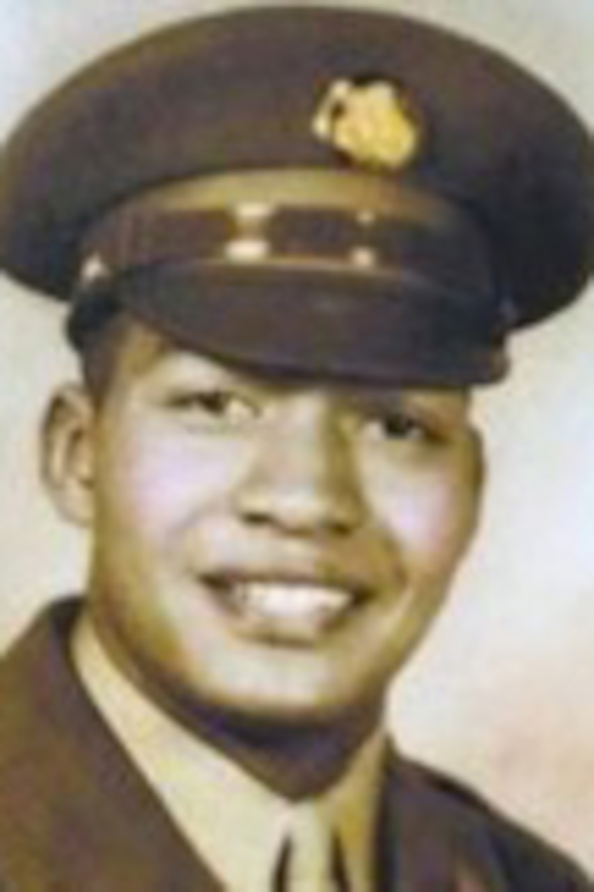 A man poses for a portrait photo wearing combat uniform.