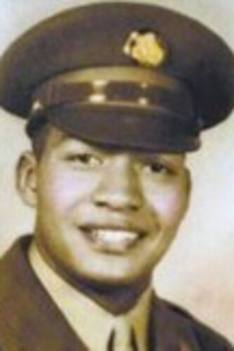 A man poses for a portrait photo wearing combat uniform.