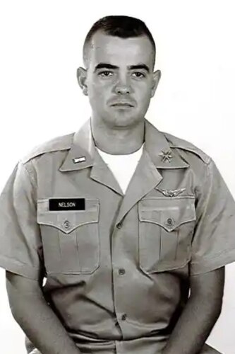 A man poses for a portrait photo wearing combat uniform.