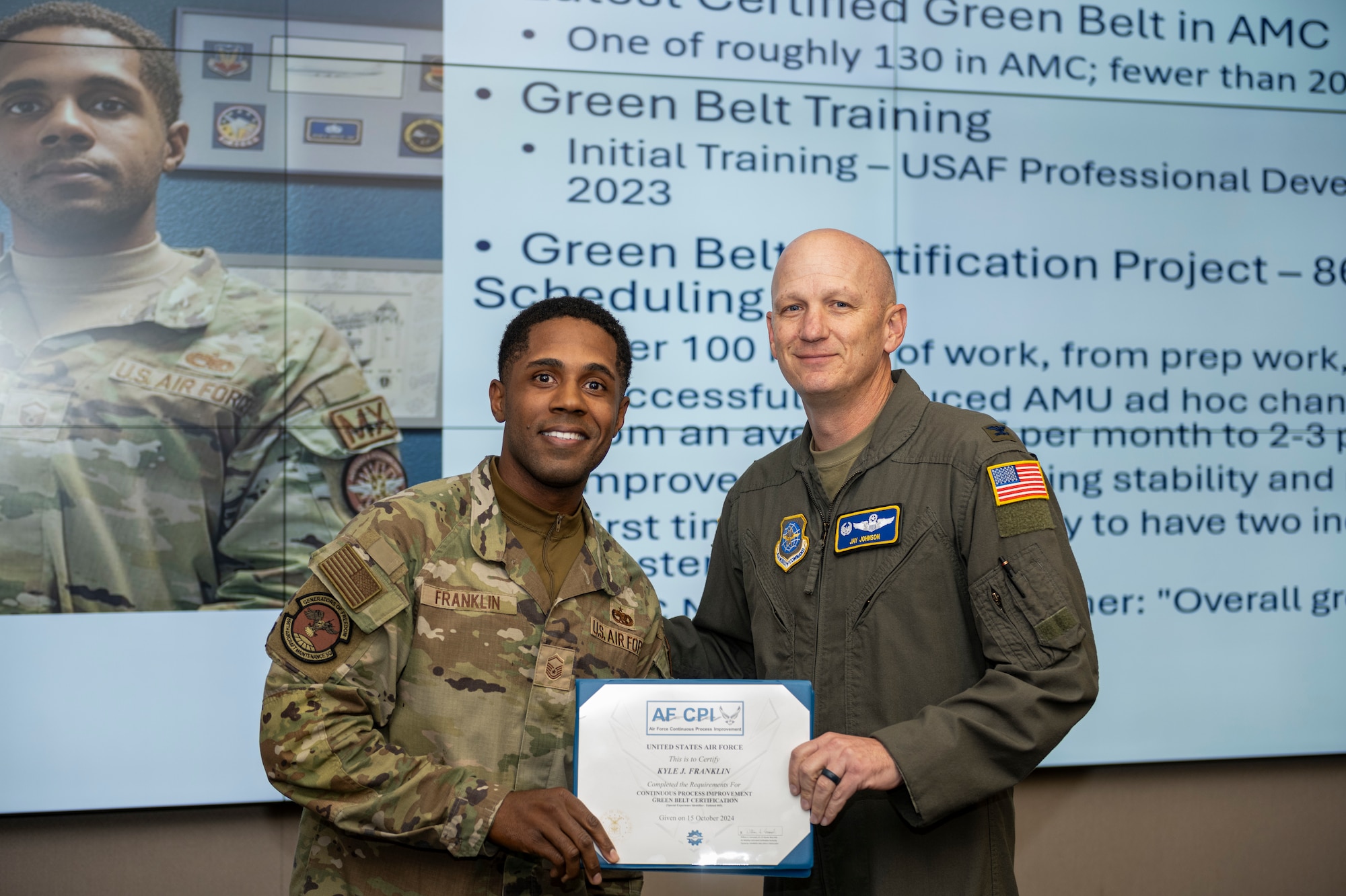 Commander stands with Airman holding a certificate