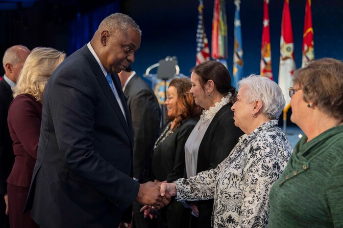 Secretary of Defense Lloyd J. Austin III shakes hands with one of a group of civilians.