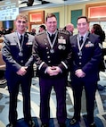 Staff Sgt. Jason Capostagno, left, and Staff Sgt. Curtis Grady, right, with the New York Air Guard’s 222nd Command and Control Squadron, stand with Gen B. Chance Saltzman, chief of Space Operations, U.S. Space Force, at the Space Force Association's Spacepower Conference in Orlando Fla., Dec.10-12, 2024. Capostagno was named the winner of the Space category, while Grady won the Intelligence category award.