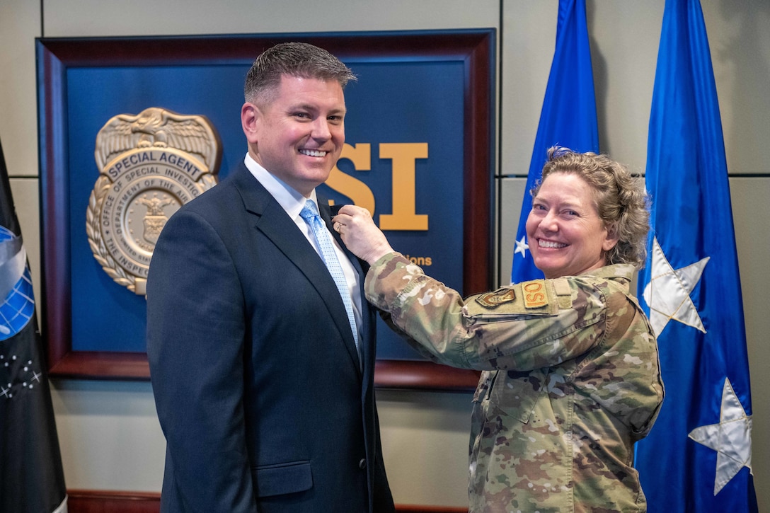 Brig. Gen. Amy Bumgarner, Air Force Office of Special Investigaions commander, pins the Senior Executive Service pin to the lapel of Special Agent Les Bernys' suit jacket, Dec. 16. As an SES leader, Bernys will lead to lead the Department of Defense Cyber Crime Center (DC3) and its evolving cyber mission.