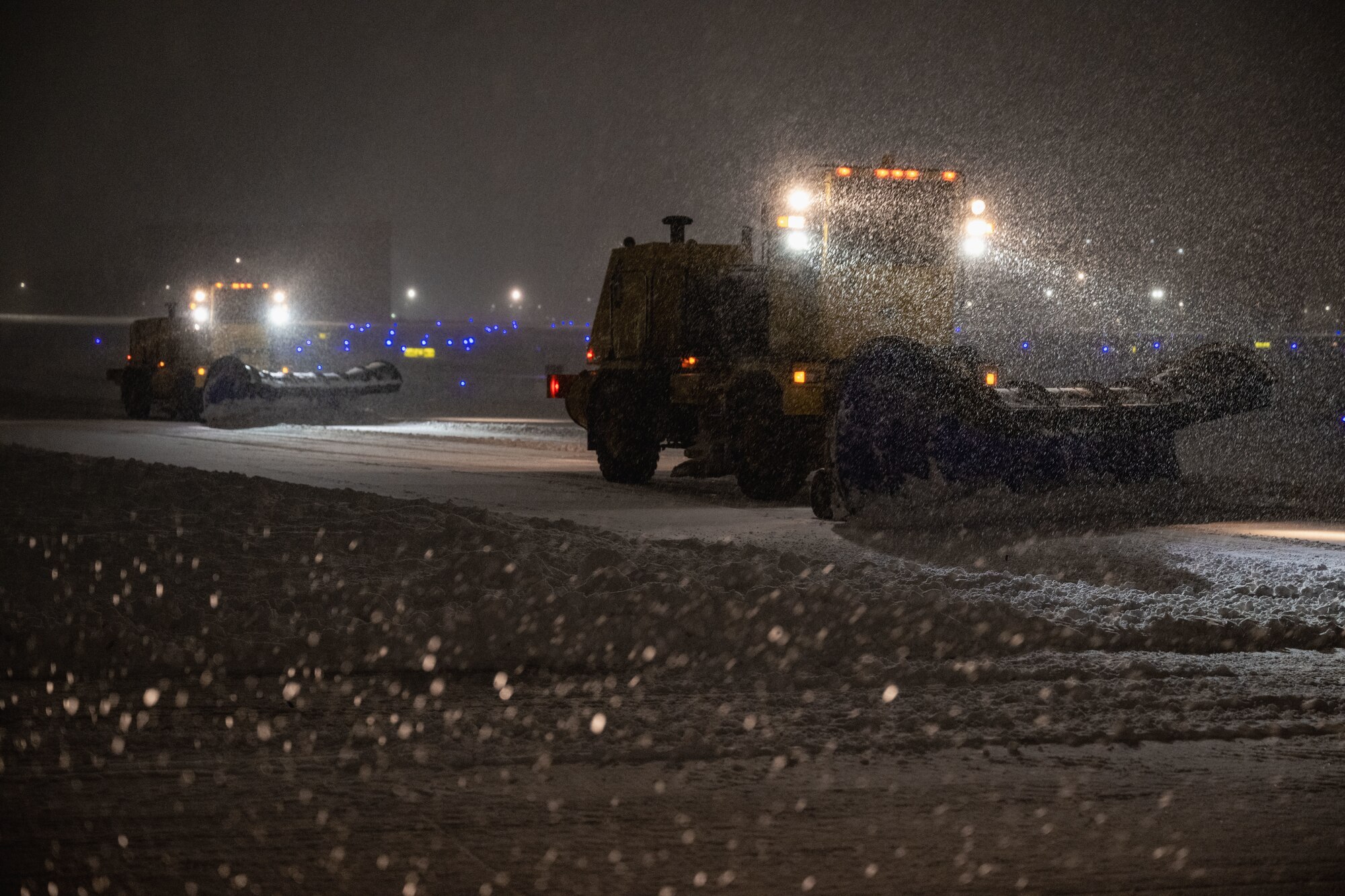 Airmen operate snowplows on the flight line.