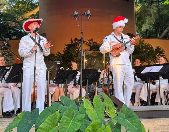 Musician 2nd Class Brenton Mitchell (left) sings and Musician 2nd Class Dan Caton plays the ukulele (right) during the holiday concert for Navy families and guests in the Luau Garden of the Hale Koa Hotel on Dec. 20, 2024. The U.S. Pacific Fleet Band is dedicated to providing top quality musical support throughout a 100 million square mile area of responsibility for official functions, morale and retention programs, community outreach performances, and Navy recruiting initiatives. (U.S. Navy photo by Kyler Hood)