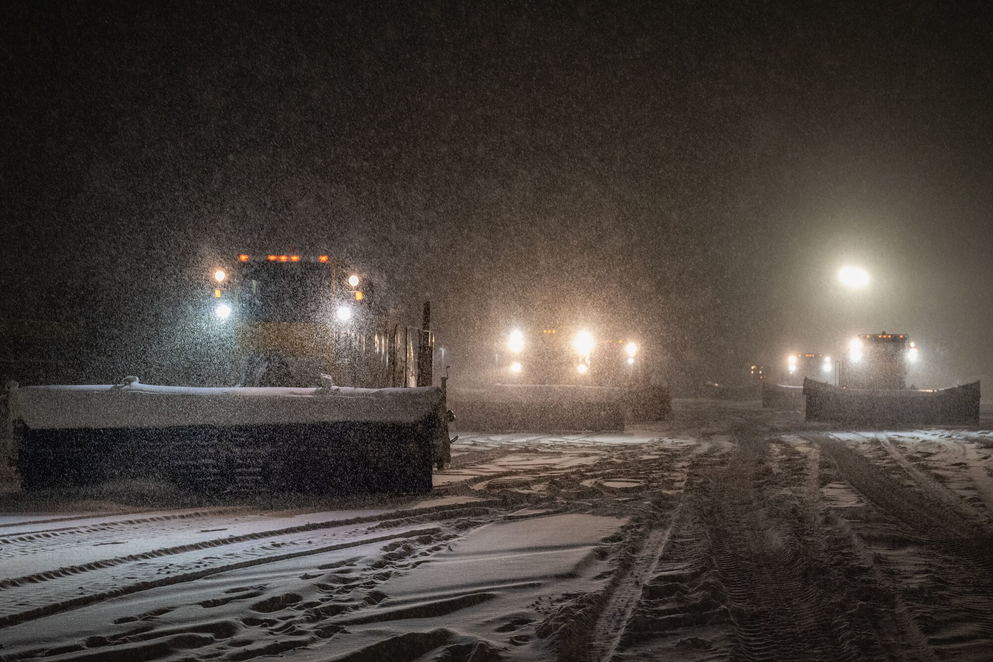 Snowplows prepare to scrape snow off of the airfield.