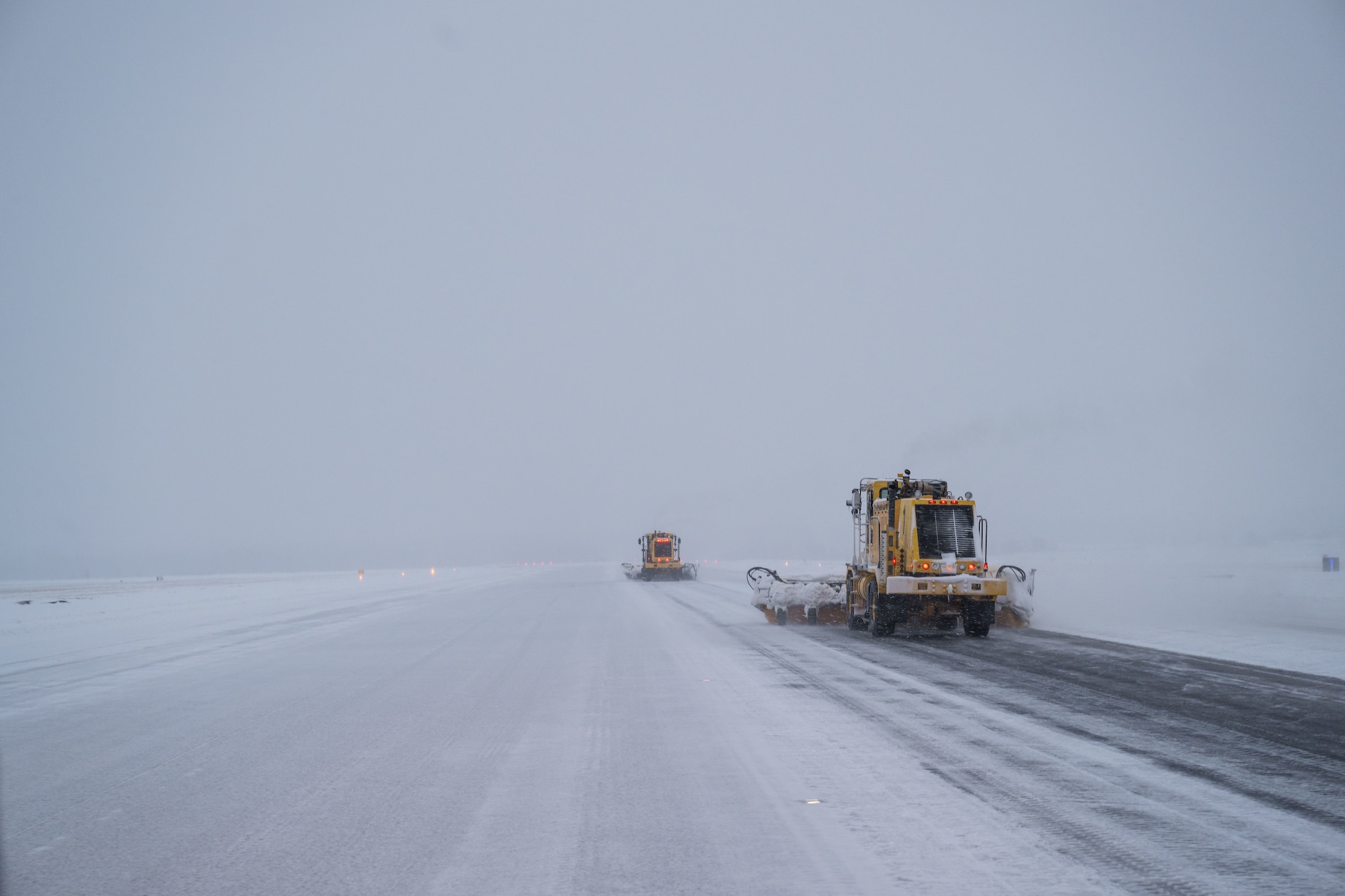 Snow brooms brush the runway free of snow.
