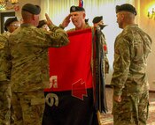 A longstanding Army tradition, the incoming Joint Multinational Training Group – Ukraine commander, Col. Christopher Costello, unfurls the brigade colors during a transfer of authority ceremony at Grafenwoehr, Germany, Oct. 1, 2024. Headquarters and Headquarters Company, 56th Stryker Brigade Combat Team, Pennsylvania National Guard assumes authority of the JMTG-U mission from Task Force Thunder, 155th Armored Brigade Combat Team, Mississippi National Guard. JMTG-U’s training of members of the Armed Forces of Ukraine helps develop the skills of Ukrainian units to conduct joint maneuver and combined arms operations and builds on specialized, individual, and collective training facilitated by U.S. Allies and partners.  (U.S. Army National Guard photo by Capt. Leanne Demboski)